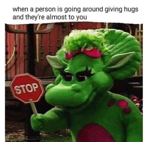Anxiety Memes, Awkward Memes, Funniest Memes, Introvert Memes, Mood Memes, People Memes, Shy Memes, Social Memes, The meme shows a green dinosaur-like children’s character standing outdoors, holding up a small red stop sign. Above the image, the text reads: “when a person is going around giving hugs and they're almost to you” followed by the emphatic “STOP” on the sign itself.