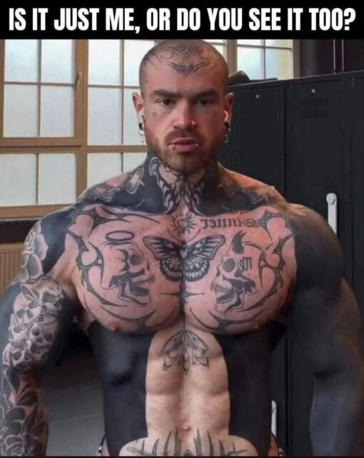 Body Building Memes, Dirty Mind Memes, Double Meaning Memes, Funniest Memes, NSFW, Optical Illusion Memes, Perspective Memes, Tattoo Memes, Weird Memes, When You See It, WTF Memes, A shirtless, heavily tattooed, muscular man sits squarely facing the camera in what looks like a gym or locker-room setting, with windows behind him and dark lockers to the side. The bold white caption across the top asks, “IS IT JUST ME, OR DO YOU SEE IT TOO?”