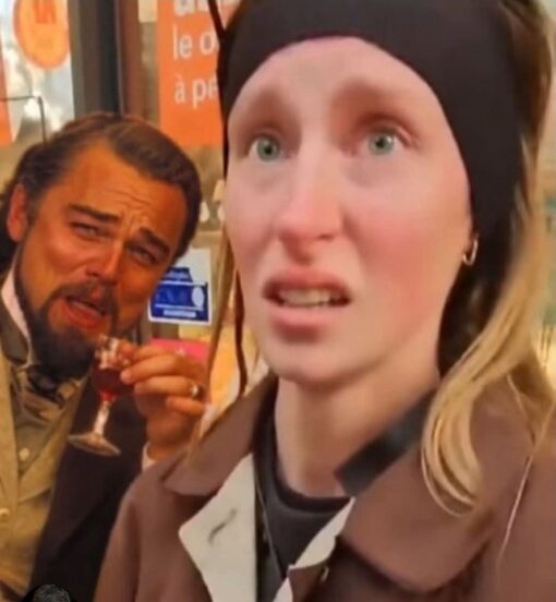Awkward Memes, Confused Memes, Funniest Memes, Funny Looking People Memes, Leonardo Dicaprio, Mashup Memes, Movie Memes, Pop Culture Memes, Voting consequences girl, Weird Memes, WTF Memes, A close-up, slightly warped photo shows a young woman in the foreground wearing a black headband, staring forward with wide eyes and a tense, caught-off-guard expression. Behind her, the familiar Leonardo DiCaprio laughing-with-a-drink reaction image is placed so he appears to be peeking in from the side, smirking at the situation.