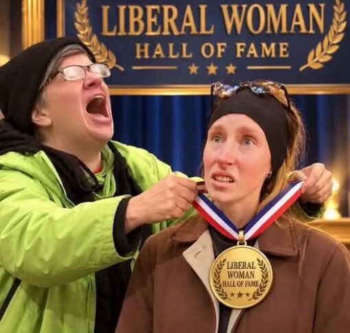 Funniest Memes, Leftist Memes, Liberal vs Conservative Memes, Offensive Memes, Political Memes, Roast Memes, Stereotype Memes, Useful Idiot, Voting consequences girl, White Liberals Memes, Women Memes, The meme shows two women posed in front of a dark blue and gold “LIBERAL WOMAN HALL OF FAME” backdrop styled like an awards-stage banner, complete with laurel graphics and stars. One woman, wearing glasses and a bright green jacket, is dramatically laughing or shouting as she places an oversized medal around the neck of the seated woman beside her. The medal repeats the phrase “LIBERAL WOMAN HALL OF FAME,” turning the image into a mock ceremony. The seated woman looks wide-eyed and uneasy, which makes the grand award presentation feel intentionally awkward and exaggerated.
