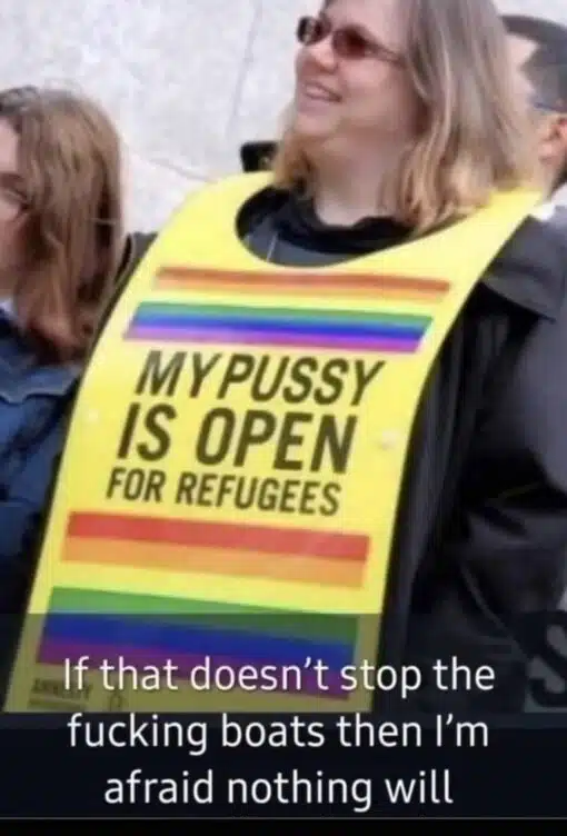 Activist Memes, Boat Memes, Current Event Memes, Dirty Mind Memes, Dirty Talk Memes, Funniest Memes, Immigration Memes, LGBTQ+ Memes, NSFW, Political Memes, Protestor Memes, Sex Memes, Vagina Memes, The image shows a smiling woman at what appears to be an outdoor protest or public demonstration, wearing a bright yellow placard over her clothing. The sign is decorated with rainbow-colored stripes and carries the large, deliberately shocking slogan: “MY PUSSY IS OPEN FOR REFUGEES.” A second caption is overlaid at the bottom of the image in white text against a dark background, adding the punchline: “If that doesn't stop the fucking boats then I'm afraid nothing will.” The overall visual has the feel of a candid protest photo turned into a crude political reaction meme.