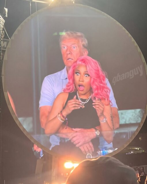 Celebrity Memes, Current Event Memes, Donald Trump Memes, Funniest Memes, Mashup Memes, Music Memes, Political Memes, Pop Culture Memes, Rap Memes, Trump and Nicki’s Ass, WTF Memes, The meme shows a large circular screen or projection displaying Donald Trump standing behind Nicki Minaj with his arms around her, while both stare forward with exaggerated, wide-eyed shock. Minaj’s bright pink hair, glam makeup, jewelry, and black outfit contrast sharply with Trump’s pale blue polo and stiff, startled expression.