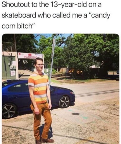 Bitch Memes, Food Memes, Funniest Memes, Funny Text Memes, Insult Memes, Kid Memes, Mean Comment Memes, Old vs Young Memes, Parking Memes, Roast Memes, Rude Memes, Savage Memes, Teen Memes, A text-post style meme shows the caption, “Shoutout to the 13-year-old on a skateboard who called me a "candy corn bitch"” above a photo of a man standing outdoors in bright daylight. He is wearing a striped shirt in yellow, orange, and white tones with brownish-orange pants, which makes the insult visually click almost immediately.