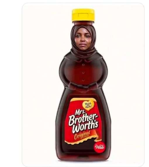 Double Meaning Memes, Food Memes, Funniest Memes, Grocery Memes, Innuendo Memes, Weird Memes, WTF Memes, The image shows a parody syrup bottle on a plain white background, styled like a grocery-store pancake syrup container with a bright yellow flip-top cap, dark amber syrup inside, and a red product label. The bottle’s upper half has been edited into the shape of a woman’s body wearing dark, syrup-colored clothing, with a woman’s face and head covering integrated into the neck of the bottle.